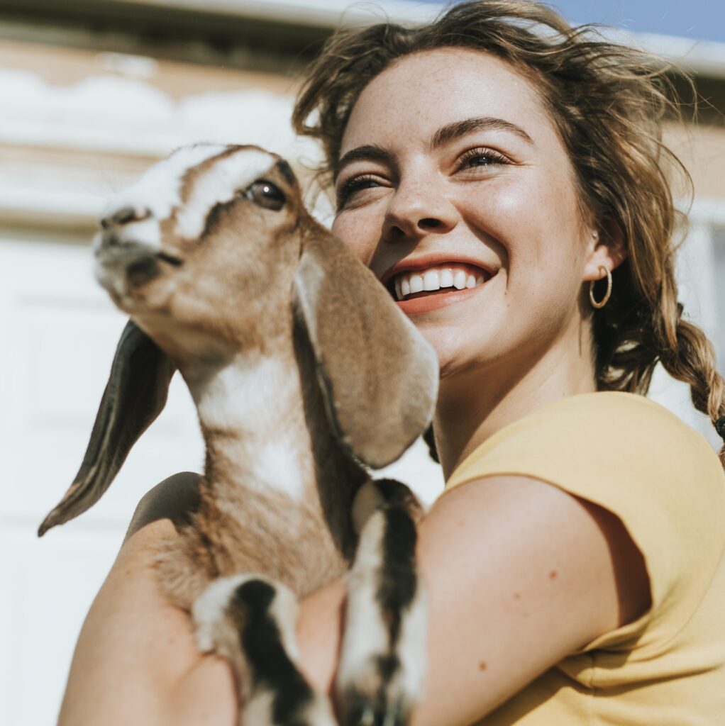 Portrait of a beautiful young woman with a goat